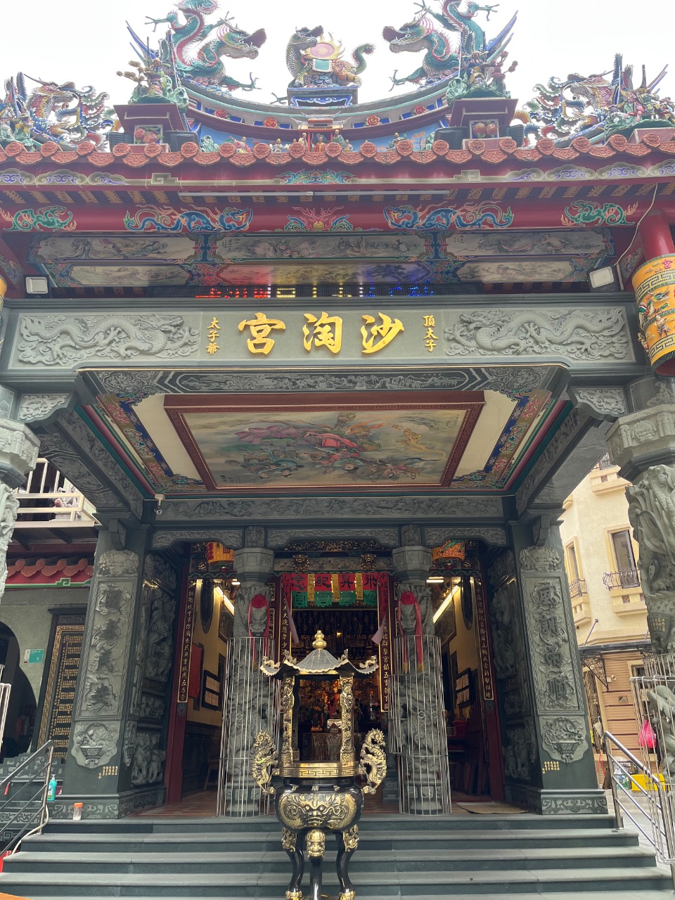 沙淘宮廟門正面，屋頂雙龍裝飾，門前一座銅製香爐。