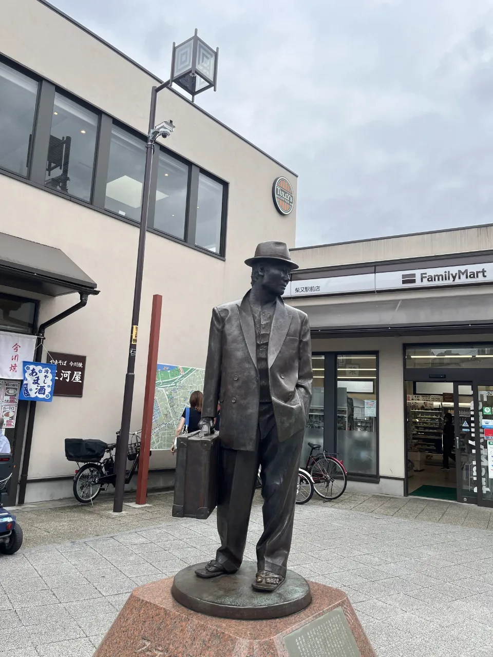 柴又駅前に立つ寅さんの銅像、後方にファミマとタリーズ