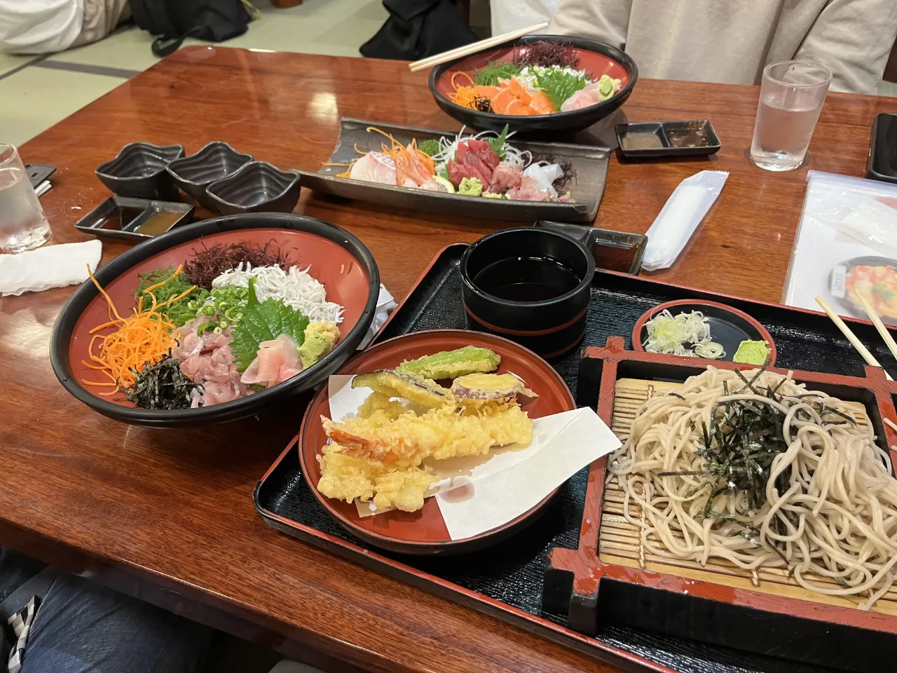 座敷のテーブルに並ぶしらす丼、天ぷらとそば、刺身の大皿
