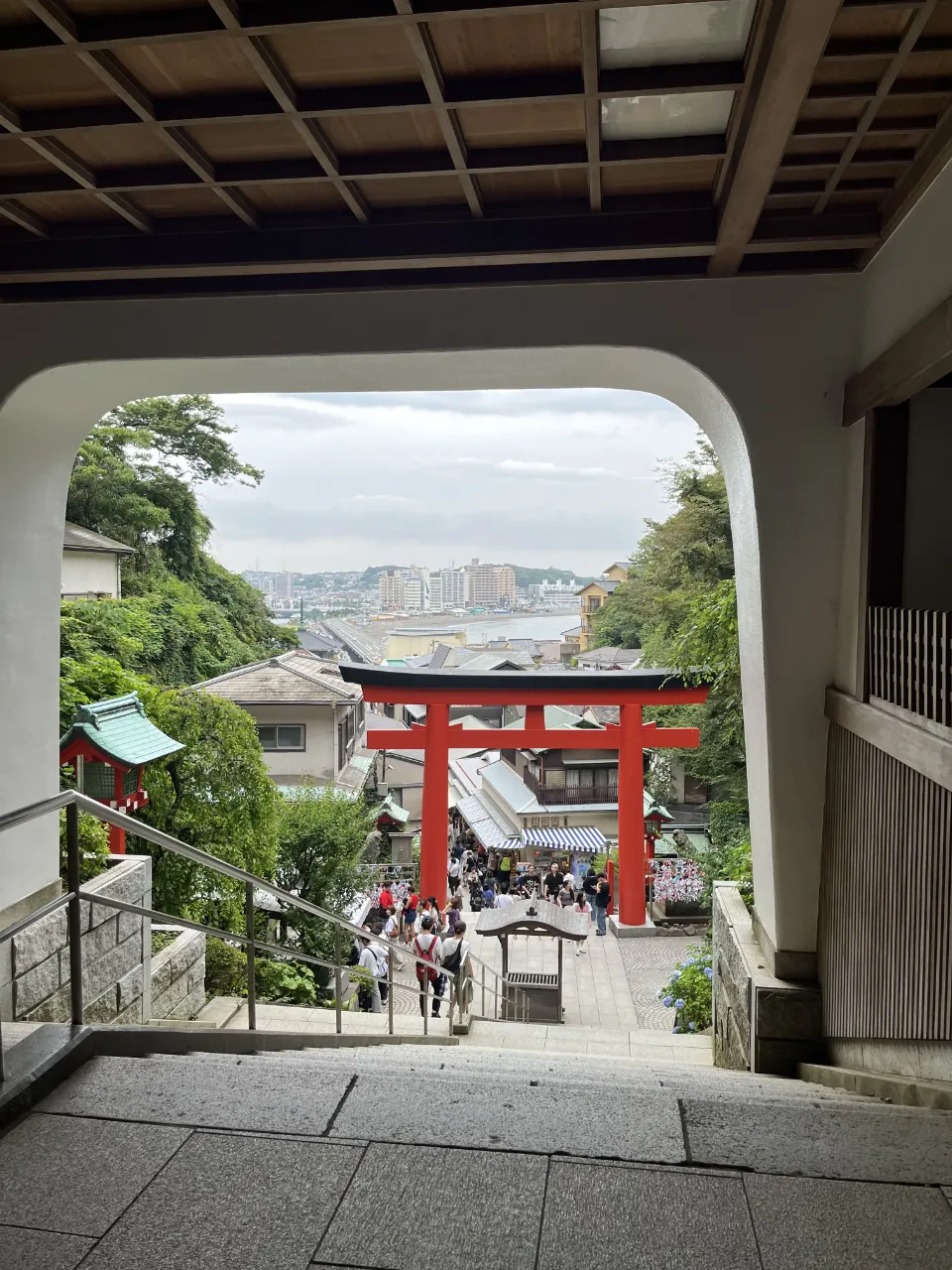 江島神社御神門往下望，紅色鳥居、商店街與遠處海景。