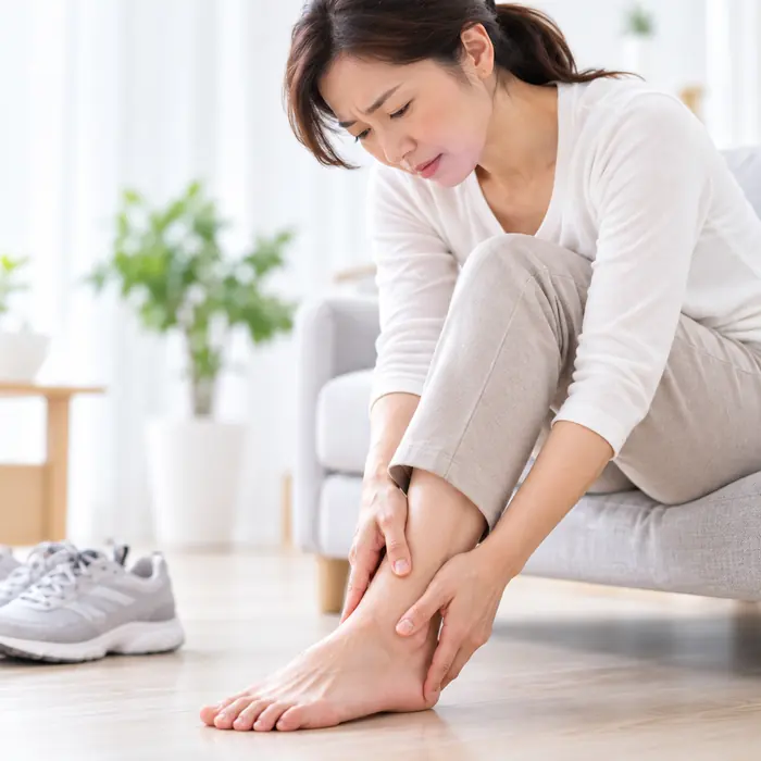 女性坐著按壓腳踝